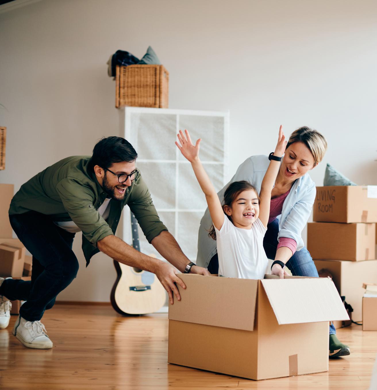 משפחה מחייכת בסלון הדירה עם ארגזים ברקע A Smiling Family in the Apartment Living Room with Boxes in the Background