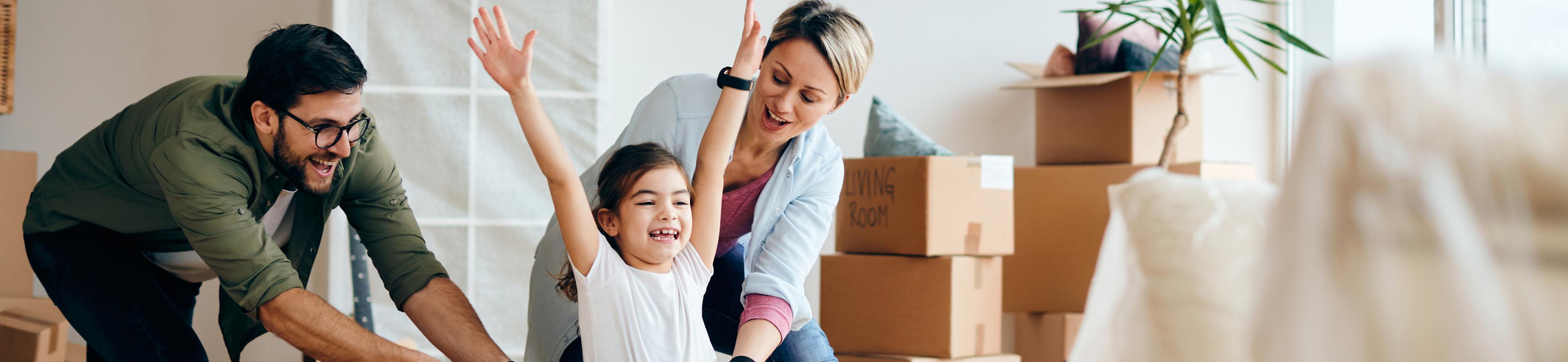 משפחה מחייכת בסלון הדירה עם ארגזים ברקע A Smiling Family in the Apartment Living Room with Boxes in the Background